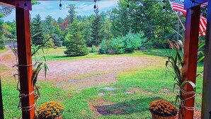 A covered outdoor area with a gravel path, surrounded by greenery and two potted plants. - Cozy 2-bedroom cabin in welcoming Sangerville with WiFi (Sangerville)