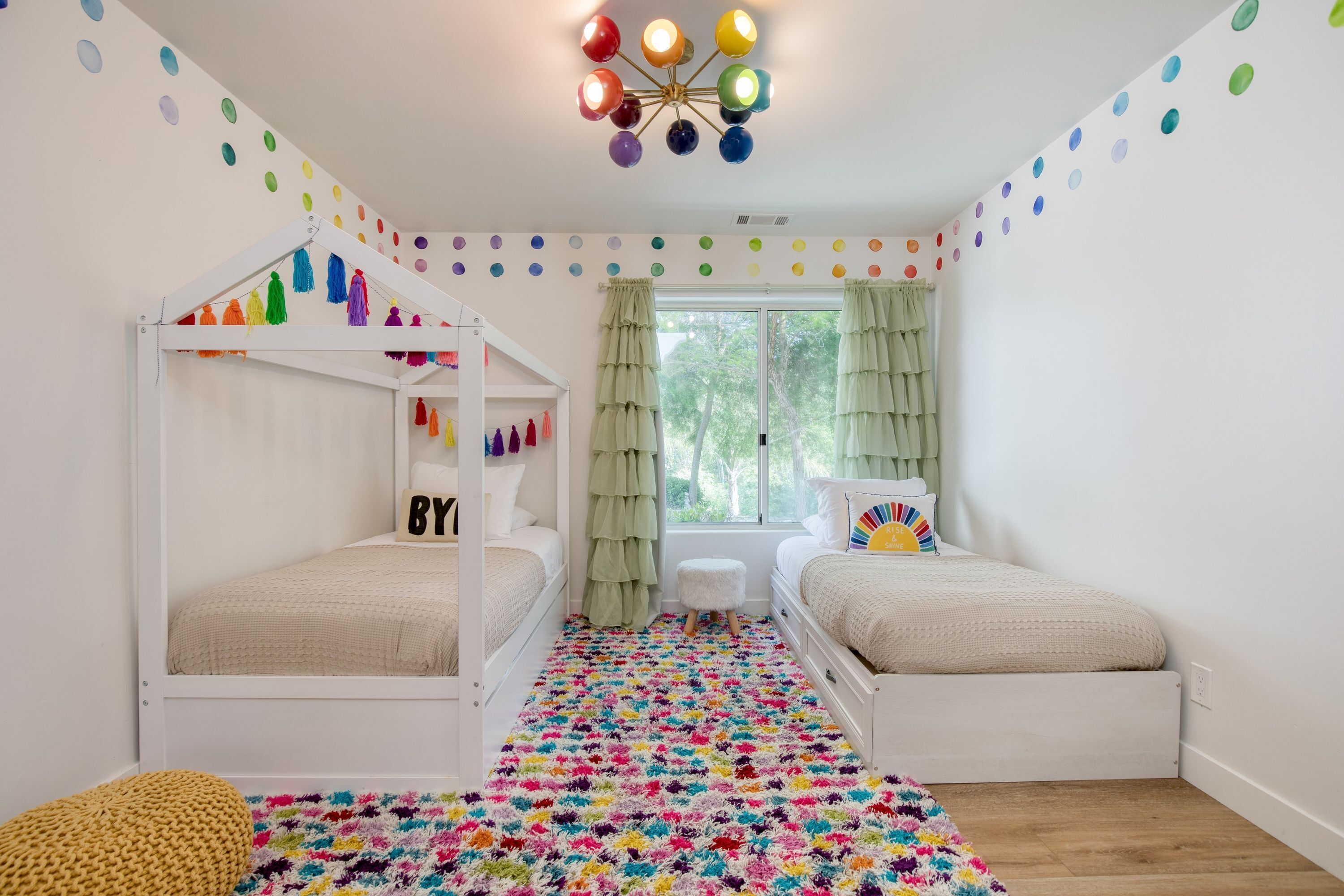 Quarto de criança com beliches, tapete colorido e luminária no teto.