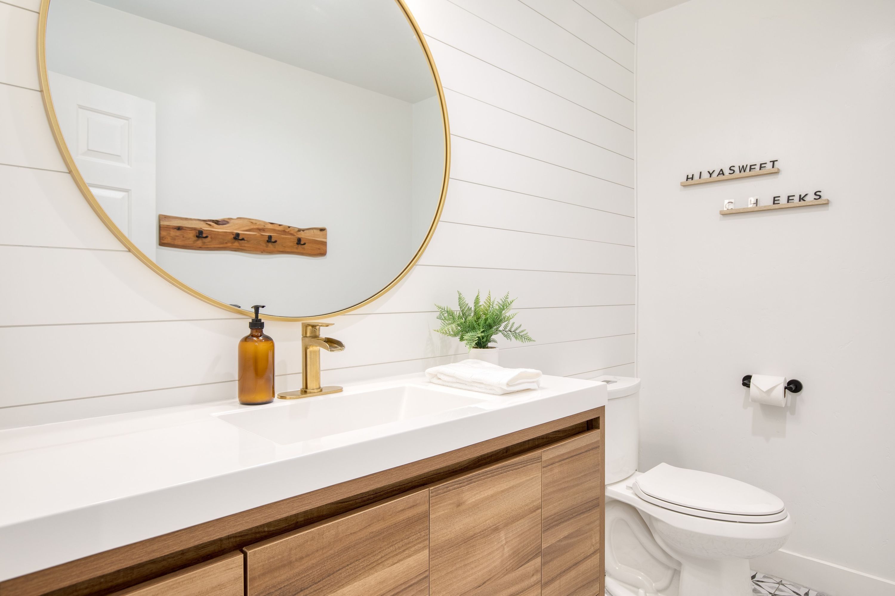 Une salle de bain moderne avec un meuble-lavabo blanc, un robinet doré et un grand miroir.