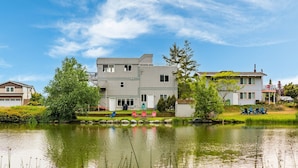 Ein modernes, zweistöckiges Haus mit großem Vorgarten, Teich und Sitzgelegenheit im Freien.