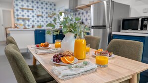 A breakfast table with fruits, a glass of orange juice, and a vase with flowers. - Fable by Avantstay 2 Unique Spaces w Bowling Hot Tub Fire Pit Large Yard (Joshua Tree)
