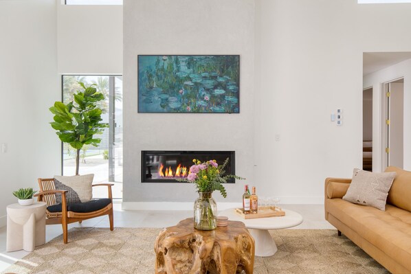 Una sala de estar moderna con chimenea, un cuadro grande y una mesa de centro de madera.