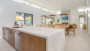 A spacious kitchen with a large island, wooden cabinets, and a dining area with a table and chairs. - The Reserve at Polo Villas 15 by Avantstay (La Quinta)