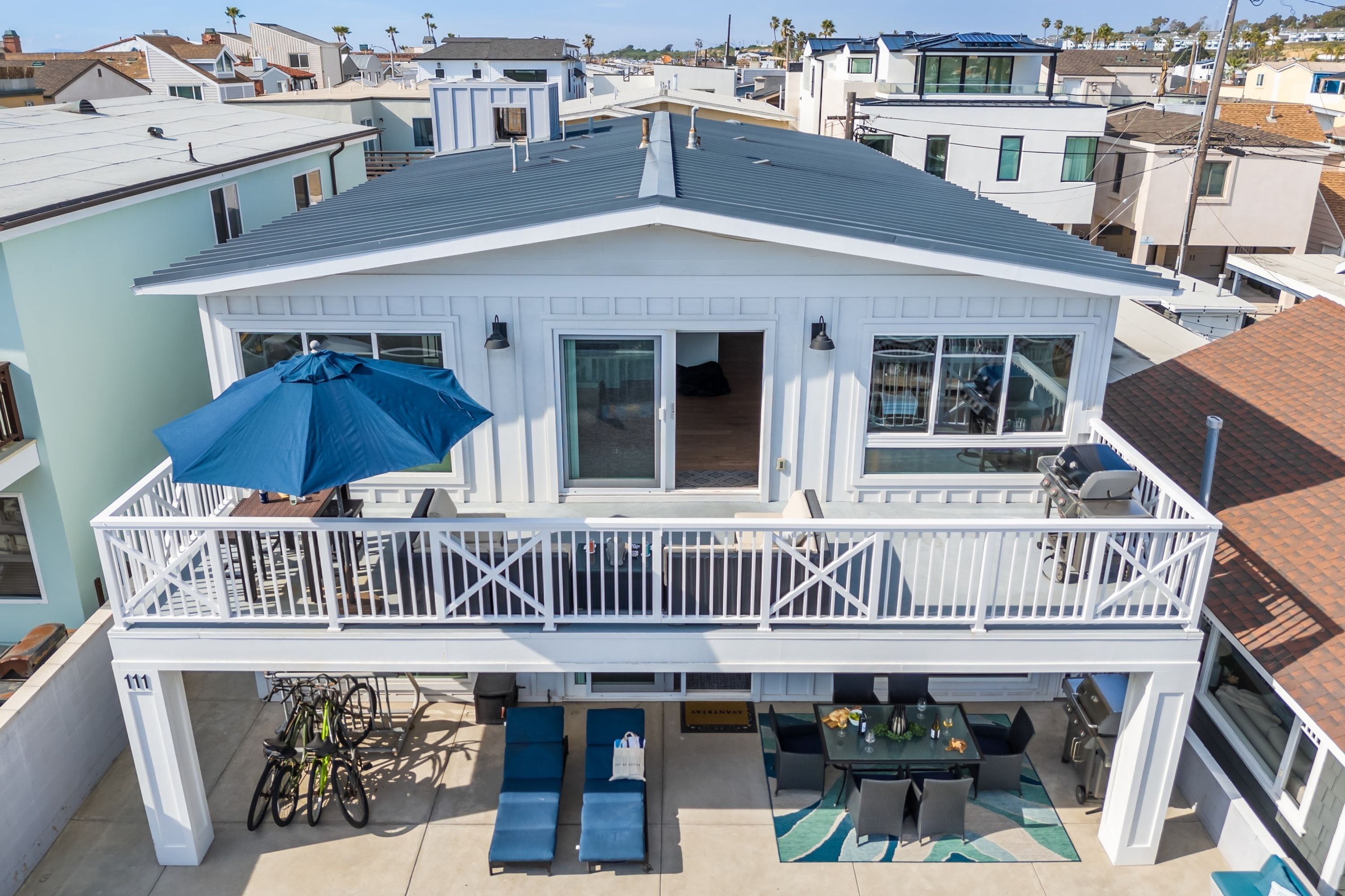 A two-story house with a balcony, outdoor seating area, and a garage.