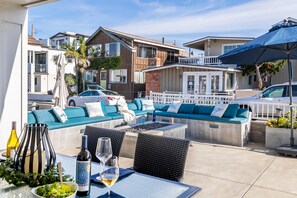An outdoor seating area with a sofa, dining table, and chairs. - Ocean Breeze Buyout by Avantstay Steps to Beach (Newport Beach)