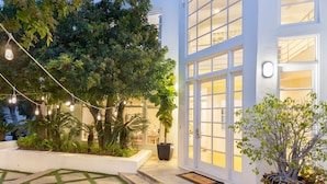 A modern building with large windows, a well-lit entrance, and a landscaped garden with potted plants. - Stardust by Avantstay Views Hot Tub Pool Table (Malibu)