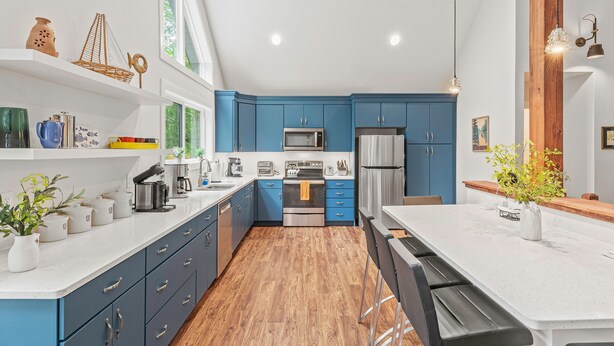 A modern kitchen with blue cabinets, a white countertop, and a wooden floor.
