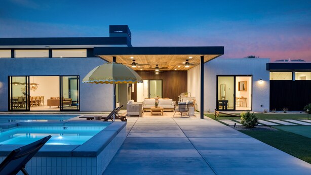 A modern house with a swimming pool, outdoor seating, and a covered patio area.
