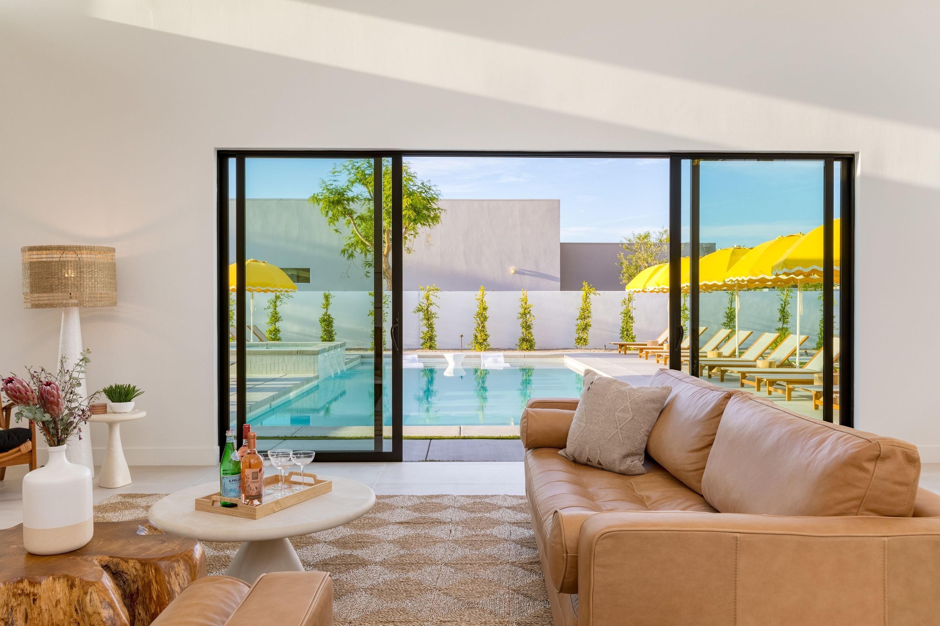 A modern living room with a large sliding glass door leading to a pool area.