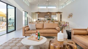 A modern living room with a large sofa, a coffee table, and a dining area in the background.