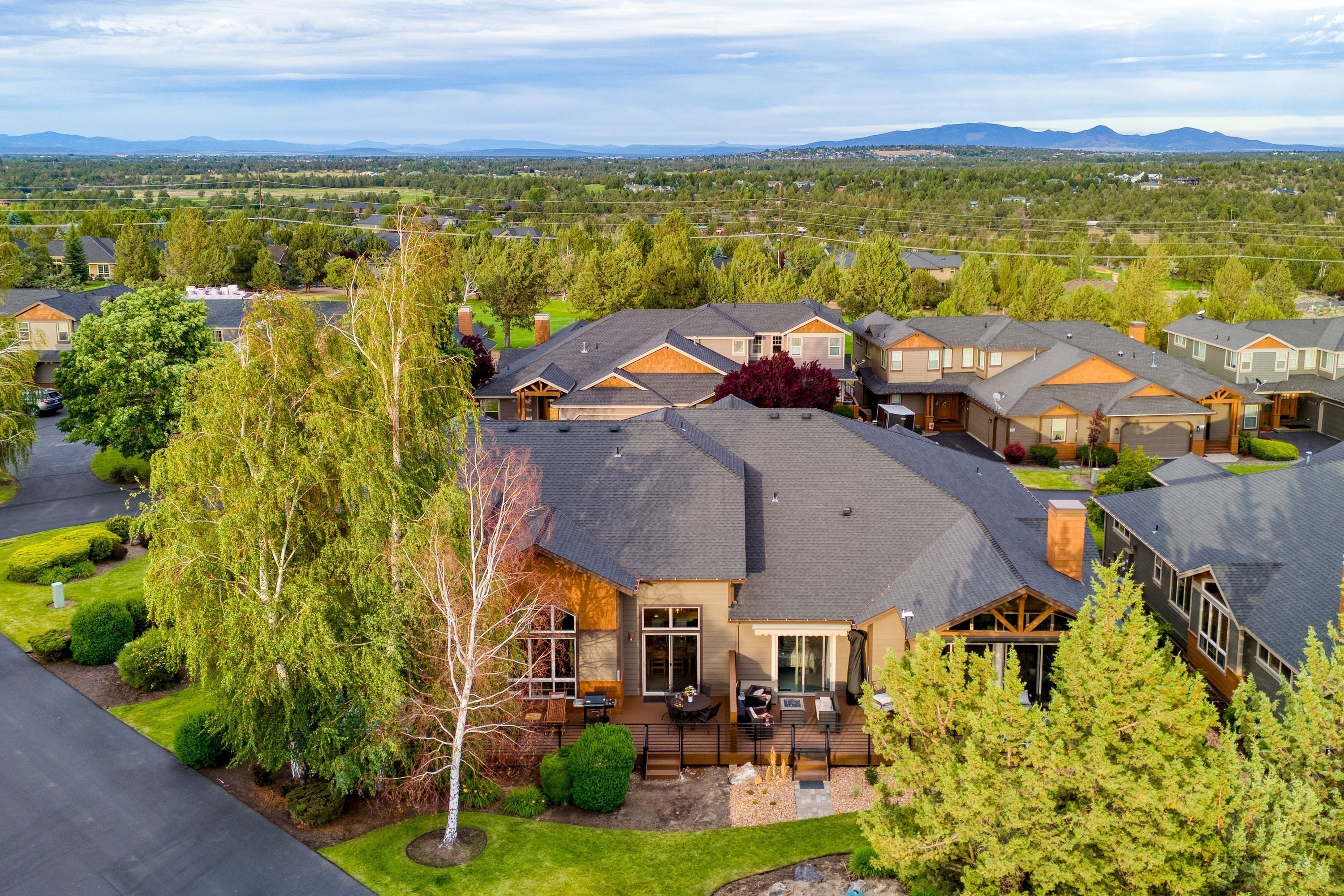 A residential area with multiple houses, well-maintained lawns, and a clear view of the surrounding landscape.