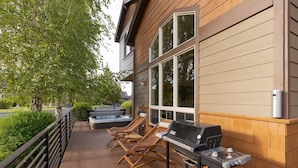Une terrasse en bois avec un barbecue et des chaises longues.