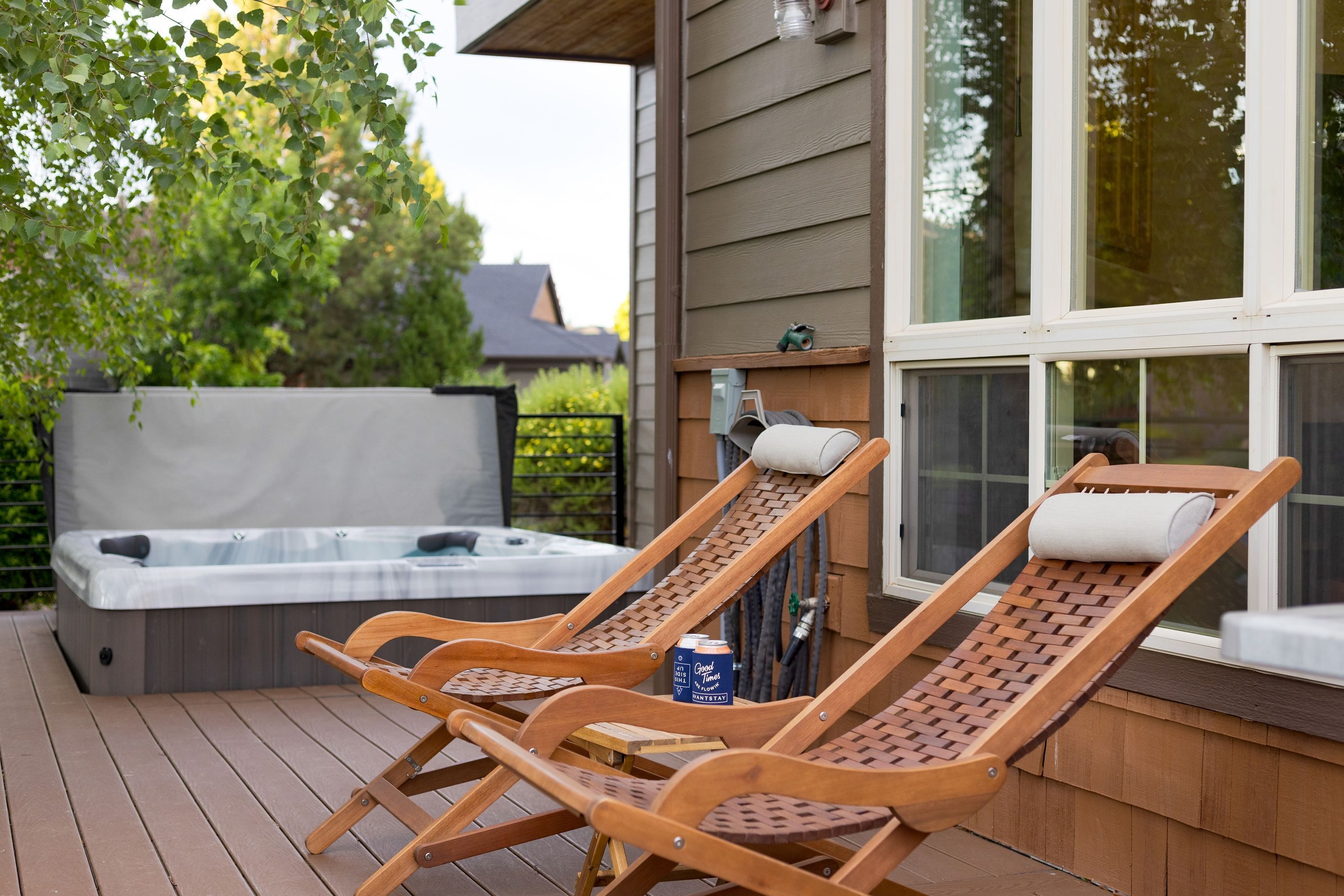 Una terrazza in legno con due poltrone relax e una vasca idromassaggio.
