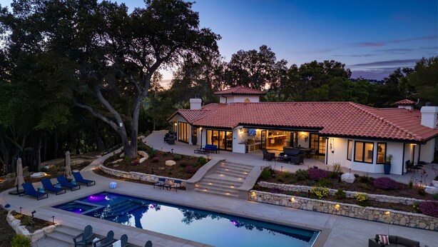 A modern house with a swimming pool, outdoor seating, and a landscaped garden.