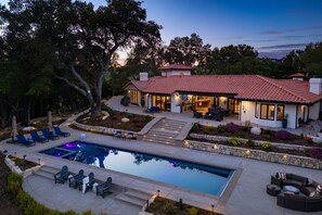 Une maison moderne dotée d’une piscine, d’un espace salon extérieur et d’un jardin aménagé.