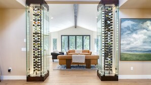 A modern living room with a glass wine rack, a sofa, and a painting on the wall.