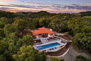 Una casa con piscina rodeada de árboles.