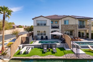 A two-story house with a swimming pool, outdoor seating, and a well-maintained lawn. - Lago Luxe by Avantstay Lakefront Private Pool Great for Festival Season (Indio)