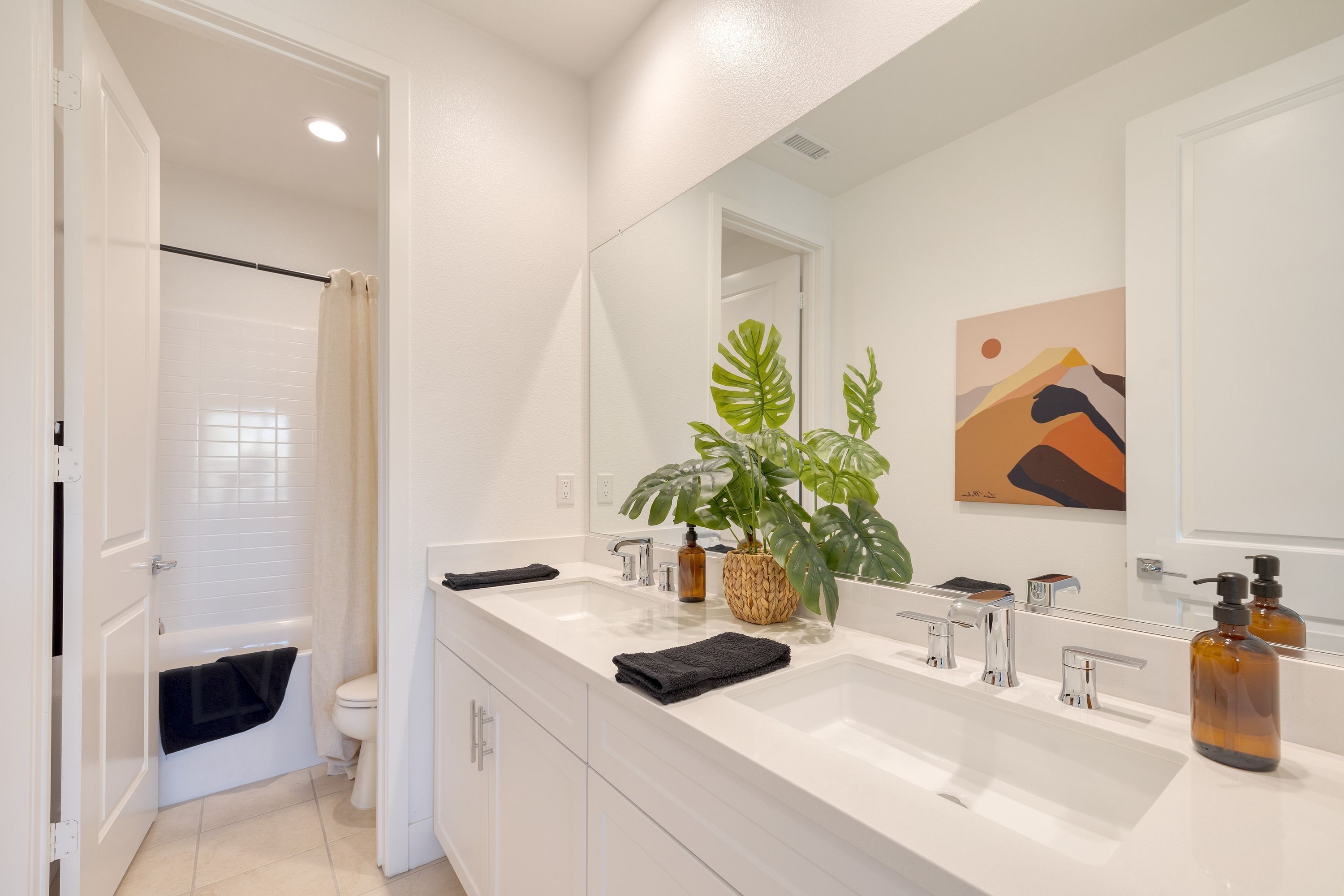 A modern bathroom with a white vanity, a large mirror, and a shower area.