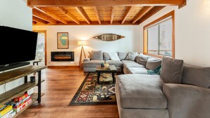 A living room with a wooden ceiling, a television, a sofa, and a coffee table.