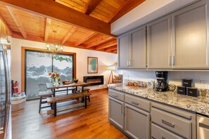 A kitchen with wooden beams, a marble countertop, and grey cabinets. - Indigo Owl by Avantstay Cabin w Firepit Minutes to Lake Slopes (Homewood)