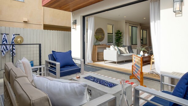 Een modern buitengebied met een pooltafel, lounge fauteuils en uitzicht op het interieur van het pand.