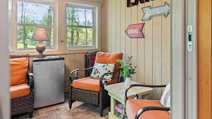 Un interior de cabaña acogedor con una mesa de comedor, un refrigerador y una silla con cojines anaranjados.