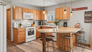 Una cocina moderna con armarios de madera, una isla central con taburetes e iluminación colgante.