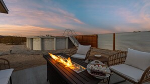 An outdoor patio with a fire feature, seating, and a view of the landscape. - Casa De Kota by Avantstay Pool Firepit Games Secluded Chic (Joshua Tree)
