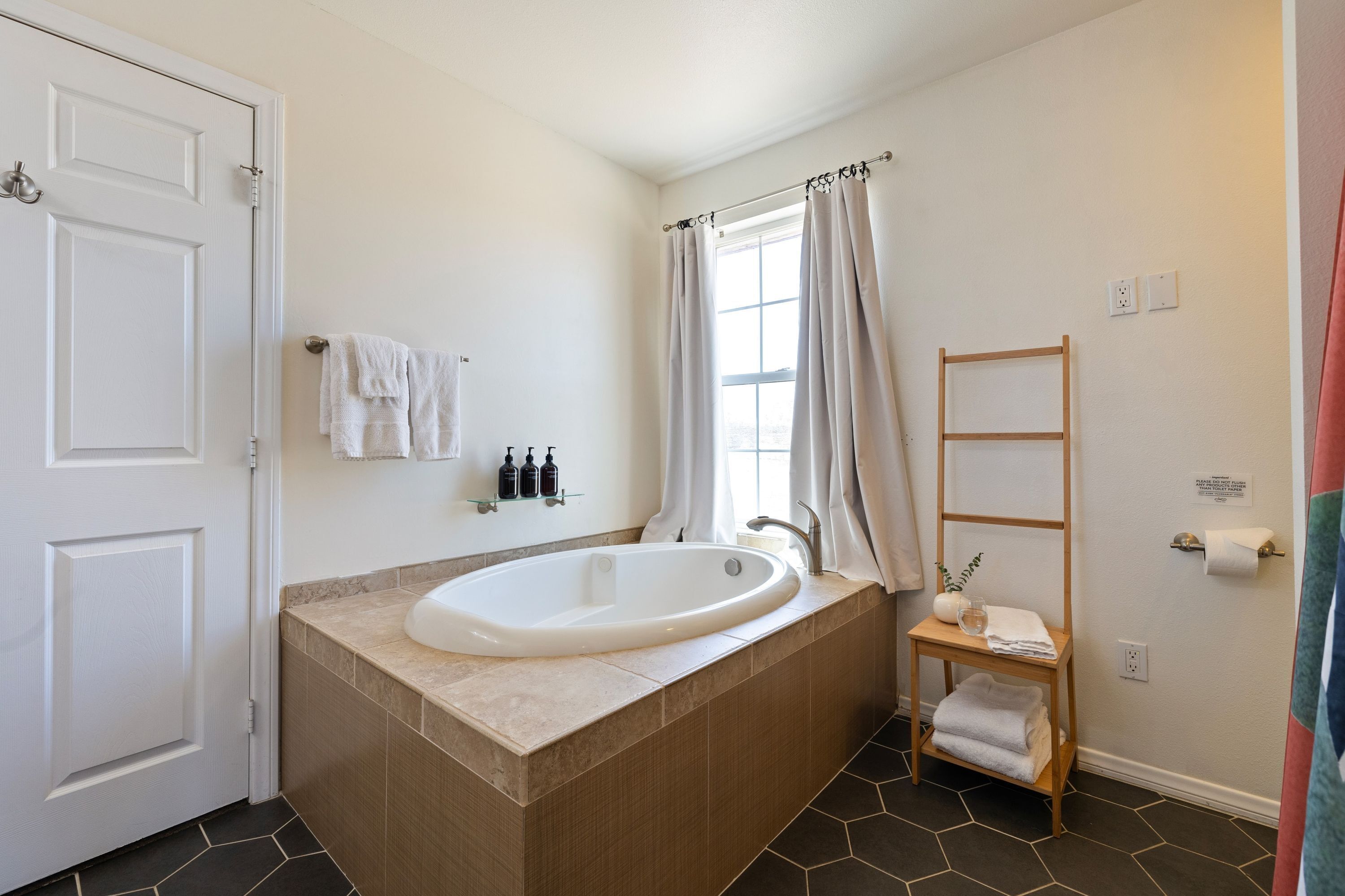 A bathroom with a freestanding bathtub, a towel rack, a shelf with toiletries, and a wooden ladder.