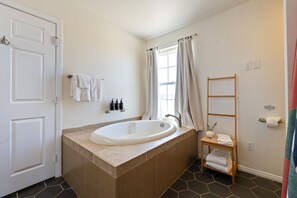 Een badkamer met een vrijstaand bad, een handdoekrek, een plank met toiletartikelen en een houten ladder.