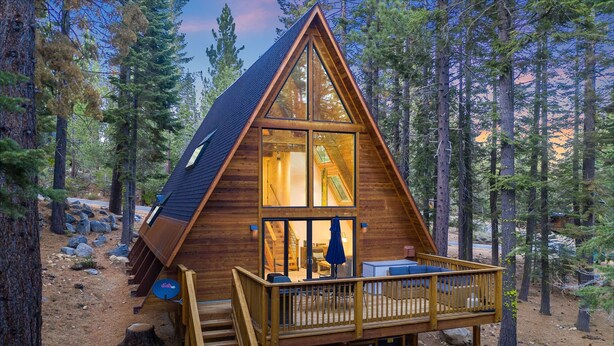 A wooden cabin with a balcony, surrounded by trees.