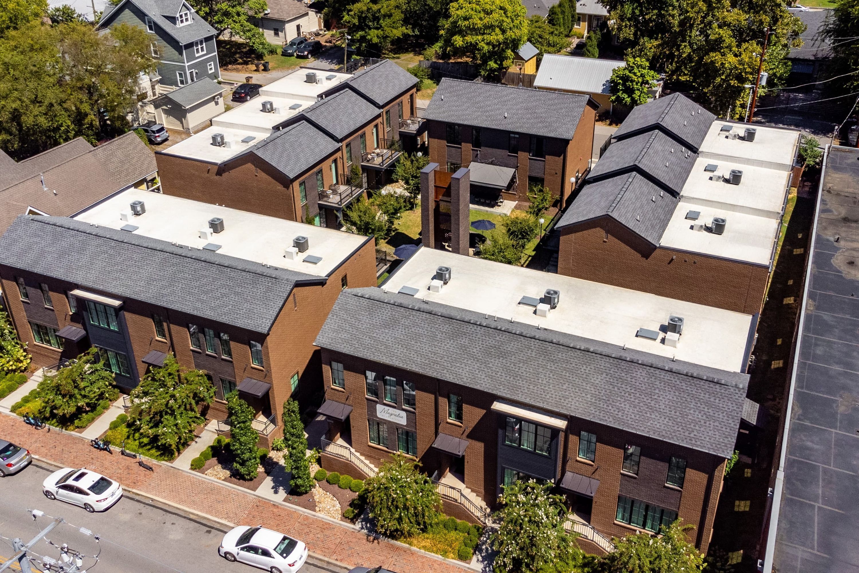 Un immeuble résidentiel à plusieurs étages, doté d’une façade en briques, de nombreux balcons et d’un toit plat sur lequel sont installées des unités de climatisation.