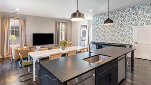 A modern kitchen with a large island, a dining area with a table and chairs, and a living area with a sofa and TV. - The Magnolia 10 - Avantstay Germantown w Private Balcony (Nashville)