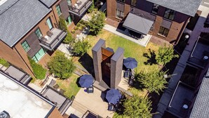 An aerial view of a courtyard with a central seating area, surrounded by buildings with brick facades and large windows. - The Magnolia 10 - Avantstay Germantown w Private Balcony (Nashville)