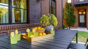 A table set with drinks and lemons, a potted plant, and a brick building in the background. - The Magnolia 10 - Avantstay Germantown w Private Balcony (Nashville)