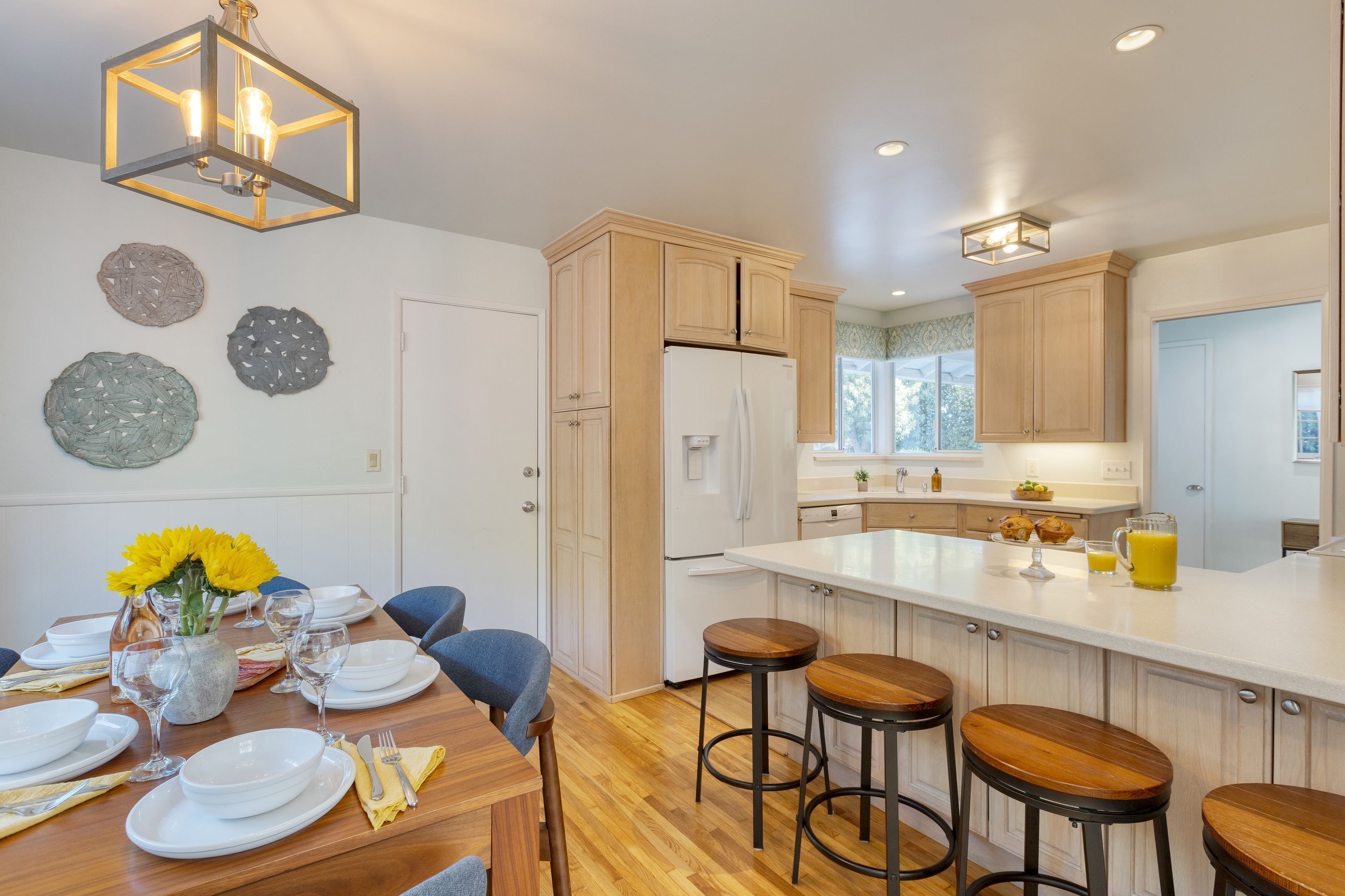 A modern kitchen with wooden cabinets, a large island with stools, and a dining area set for six.