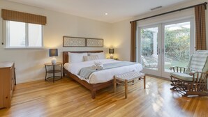 Ein Schlafzimmer mit einem hölzernen Bett, Nachttischlampen, einer Bank und einem Schaukelstuhl.