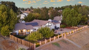 A residential house with a fenced yard, solar panels, and a view of the surrounding neighborhood.