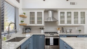 A modern kitchen with blue cabinets, a stainless steel stove, and a large sink.