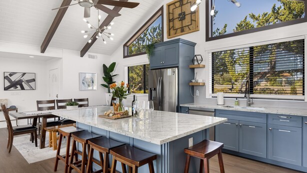 A modern kitchen with a large island, bar stools, and a ceiling fan.