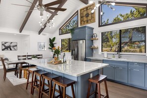 A modern kitchen with a large island, bar stools, and a ceiling fan.