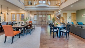 A spacious, multi-level living area with a dining table, chairs, a sofa, and a staircase. - Grays Crossing by Avantstay Stunning 4bdr Cabin (Truckee)