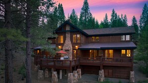A two-story log cabin with a stone chimney, wooden deck, and multiple windows. - Grays Crossing by Avantstay Stunning 4bdr Cabin (Truckee)