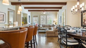 A spacious living area with a dining table, leather chairs, and a kitchen area with a bar.