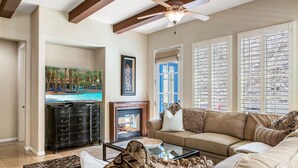 A living room with a fireplace, a sofa, a coffee table, and a television displaying a pool scene.