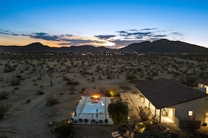 A desert landscape with a pool area and a building with a tiled roof.