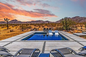 Una piscina con lettini da relax, immersa in un paesaggio desertico e montuoso.