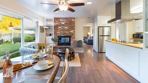 A spacious kitchen with modern appliances, a dining area with a brick wall, and a large window overlooking a garden. - East Valley Manor by Avantstay Minutes to the Beach (Santa Barbara)