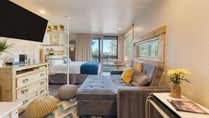 A compact bedroom with a bed, a sofa, a desk, and a TV.